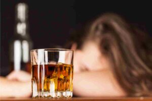 un bicchiere di whisky e dietro una persona priva di sensi